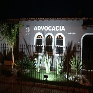 As luzes realçam a fachada contrastando com o jardim do escritório de Cerquilho/SP.